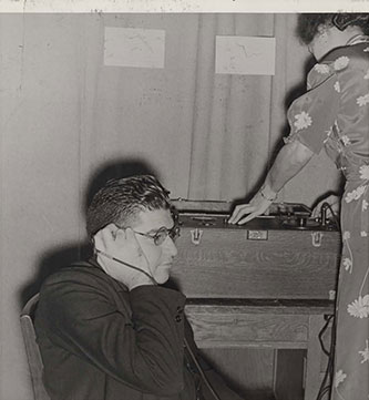 Two faculty members demonstrating audiometric testing, with what was then state-of-the-art equipment.