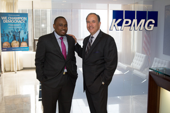 At the KPMG offices in Midtown Manhattan, Anthony Castellanos '84 (right) congratulates Craig Henry '11 on his successful academic and career trajectory. 